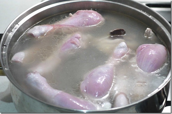 Chicken drumsticks and bones simmering in stock pot